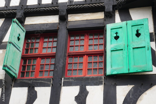 old red wooden windows with green shutters of an old half timbered house