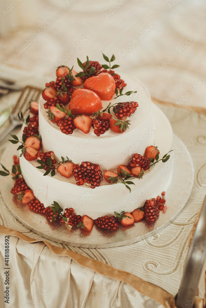 wedding cake decorated with ripe berries on a white table wedding cake decorated with ripe berries on a white table