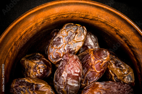 Big luxury dried date fruit in bowls on the dark surface, kurma ramadan kareem concept, close up.