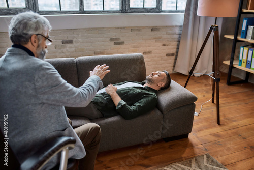 Foto Calm man on couch during appointment with psychotherapist
