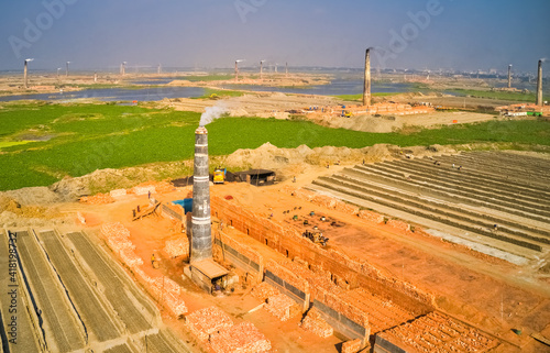 Aerial view of several chimneys from a brick factory along Karnatali tributary river near Savar city, Dhaka, Bangladesh. photo