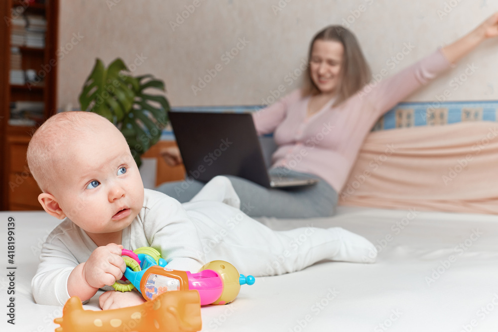 A young girl with a small child is happy to work from home on a laptop A young girl with a small child is happy to work from home on a laptop