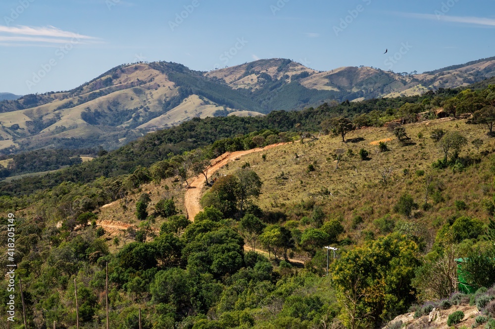 View from the observation deck of O Lavandario farm of the mountainous landscape of Cunha with dirt roads running over the hills and around pasture fields.