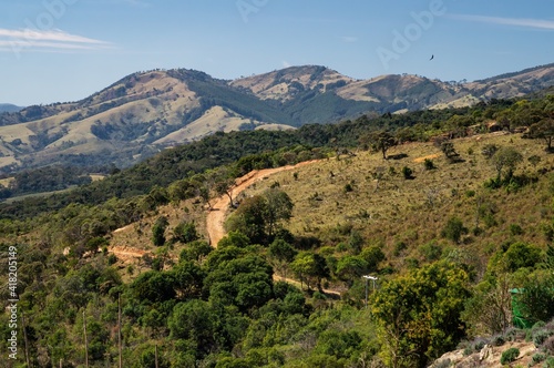 View from the observation deck of O Lavandario farm of the mountainous landscape of Cunha with dirt roads running over the hills and around pasture fields.