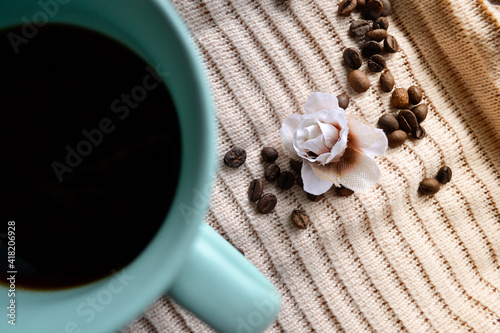 cup of coffee on knitted cloth next to coffee beans photo