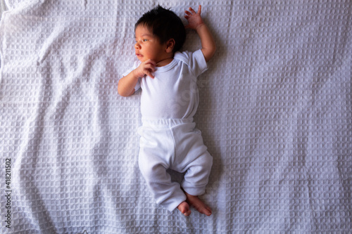 beautiful newborn hispanic baby on a white sheet, calm and relaxed