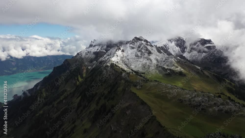 Drone shot flying sideways to the left, over Schynige Platte. Beautiful, colorful lake in the background with snow covered peaks and big clouds drifting above the amazing, picturesque landscape. Drone shot flying sideways to the left, over Schynige Platte. Beautiful, colorful lake in the background with snow covered peaks and big clouds drifting above the amazing, picturesque landscape.