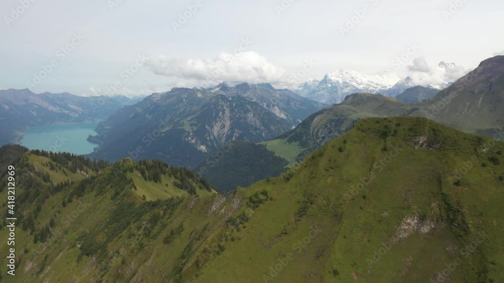 Drone shot of Morgenberghorn flying sideways high up in the sky during a sunny summer day in Switzerland. Empty, peaceful and epic landscape with turqouise lake and river in the background. Drone shot of Morgenberghorn flying sideways high up in the sky during a sunny summer day in Switzerland. Empty, peaceful and epic landscape with turqouise lake and river in the background.