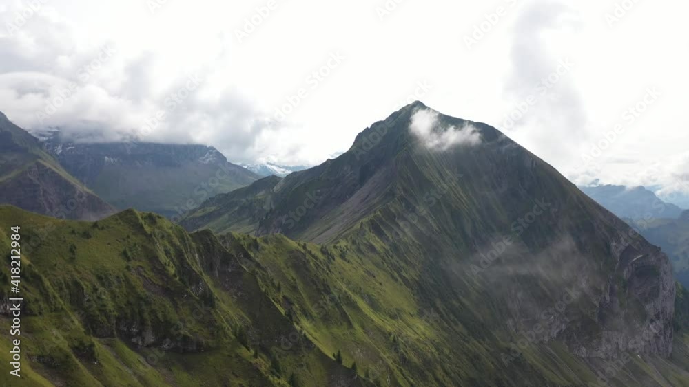 Slow and gentle drone shot of Morgenberghorn in Switzerland. Beautiful and lush landscape of green grass on the slopes. Beautiful, quiet and serene landscape during a sunny summer day with thin clouds Slow and gentle drone shot of Morgenberghorn in Switzerland. Beautiful and lush landscape of green grass on the slopes. Beautiful, quiet and serene landscape during a sunny summer day with thin clouds