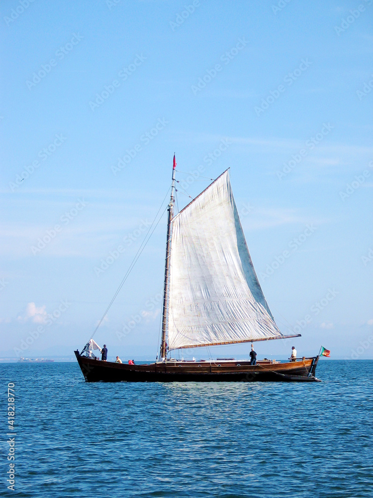 Original traditional sail boat on river Tagus in Lisboa (Portugal, Europe), authentic old commercial vessel propelled by sails.