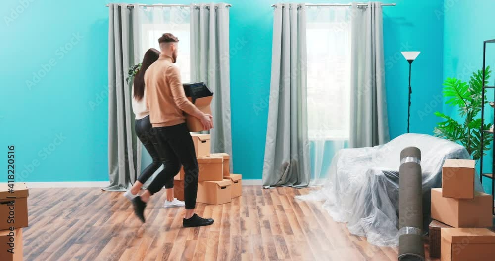 Happy married 20s couple move into new first house bring carton boxes with personal belongings to apartment celebrate relocation accomplishment giving high five feels satisfied. Loan, mortgage concept