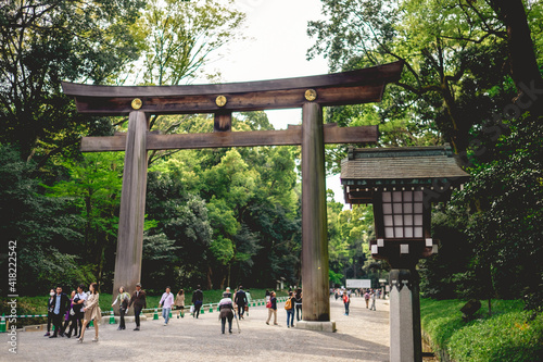 Traditional wooden lamp and great torii gate and tourist and visitors at Meiji Shrine in Yoyogi Park, Tokyo, Japan photo