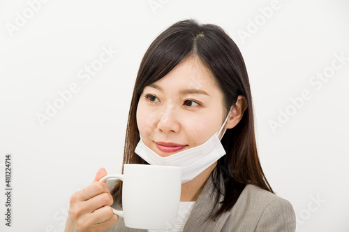 マスクを顎に掛けたまま飲料を飲む女性