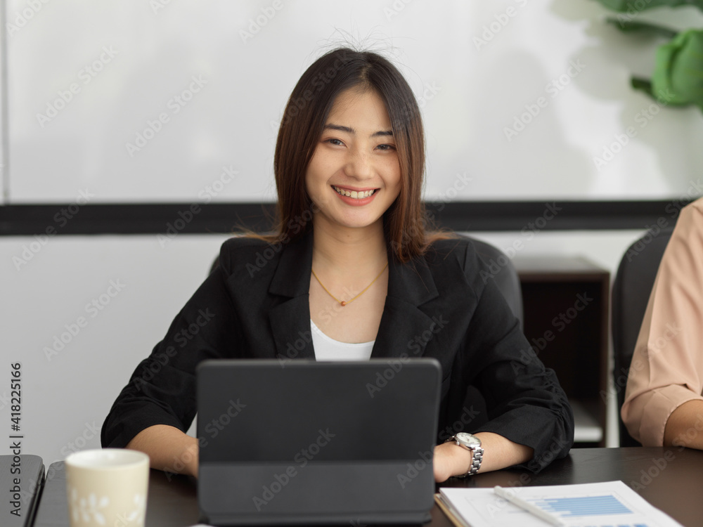 Beautiful businesswoman smiling to camera while working in meeting room Beautiful businesswoman smiling to camera while working in meeting room