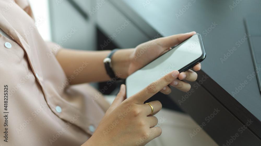 Female hands holding mock up smartphone while sitting at workplace