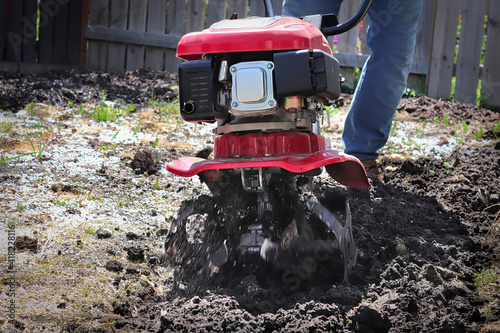 Cultivating garden soil in the spring with a rototiller photo