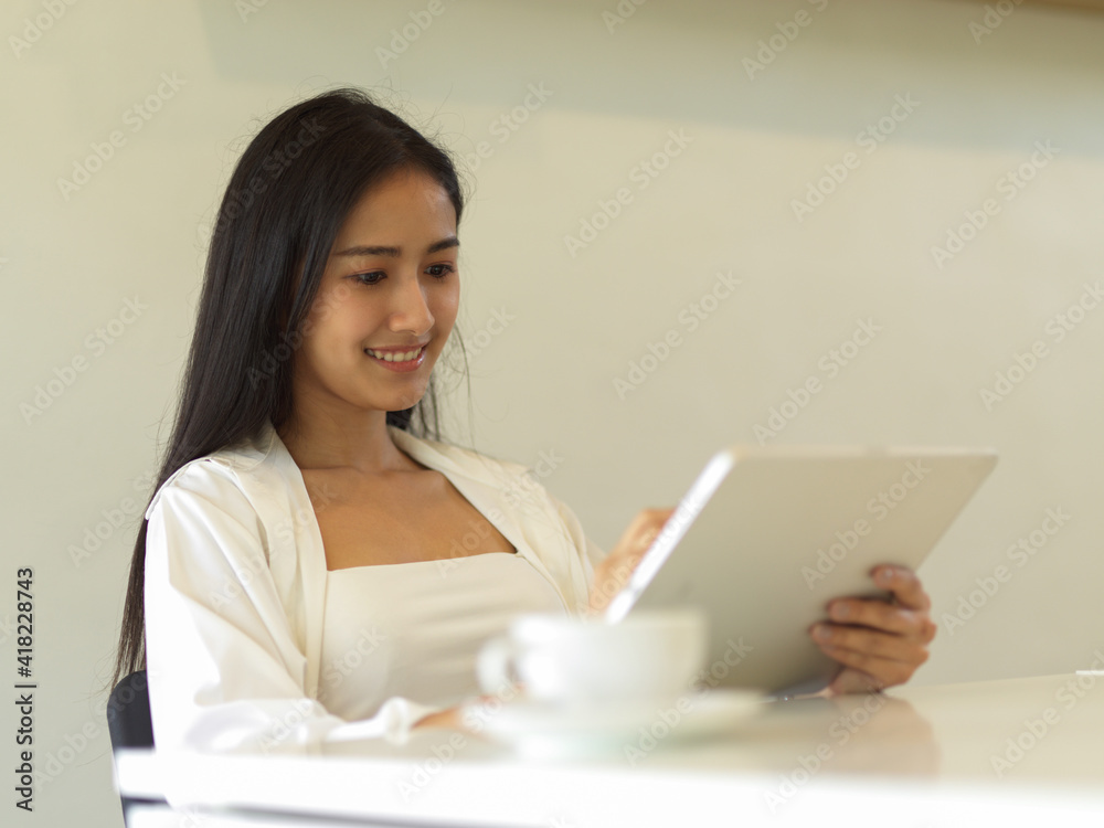 Businesswoman working with digital tablet while sitting in office room Businesswoman working with digital tablet while sitting in office room