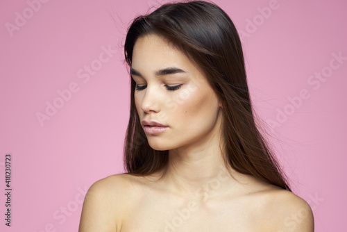 brunette bare shoulders clear skin body care pink background