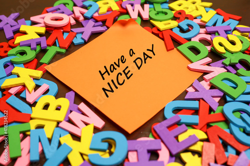 A piece of paper with a message on Have a Nice Day surrounded by colorful alphabets 