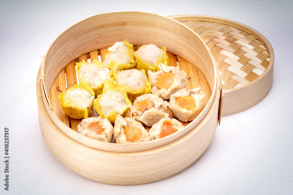 Pork and Crab Dumplings Ready to serve in an oriental woven bamboo basket on a white background