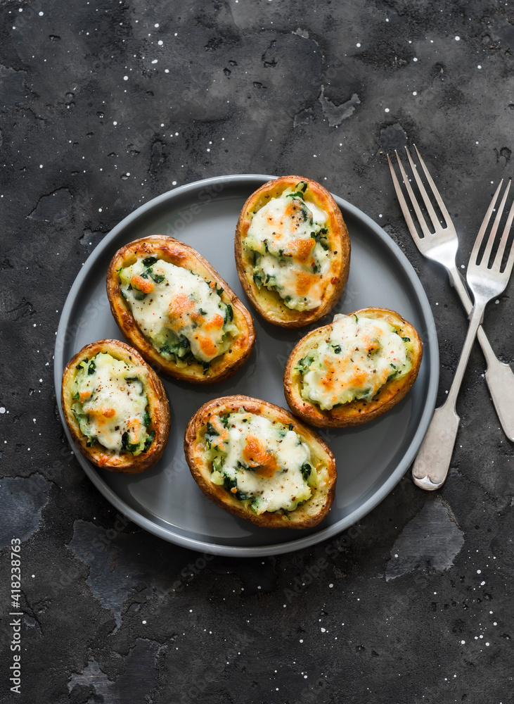Roasted potatoes stuffed with spinach and mozzarella on a dark background, top view