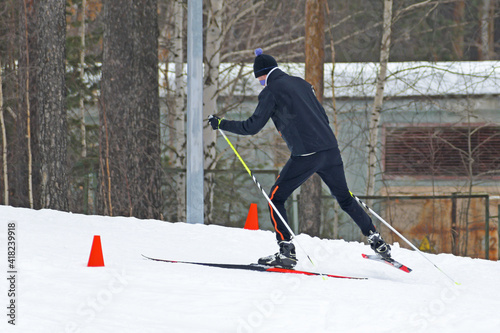 A skier runs on a ski track laid in a pine forest photo