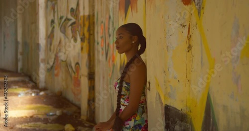 Caribbean girl stands on a graffiti wall at an abandoned building in the Caribbean photo