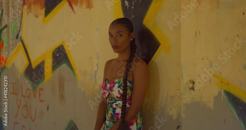 A young woman with sexy eyes stands at a wall with gafitti art in an abandoned building photo