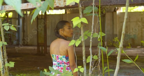A young Caribbean Queen turns and smiles while sitting in the windows of an abandoned warehouse photo