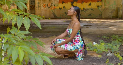 A sexy young woman squats at an abandoned warehouse with grafitti art in the background photo