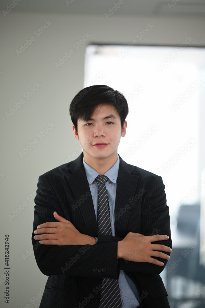 Portrait of asian businessman standing with arms crossed in modern office. Portrait of asian businessman standing with arms crossed in modern office.