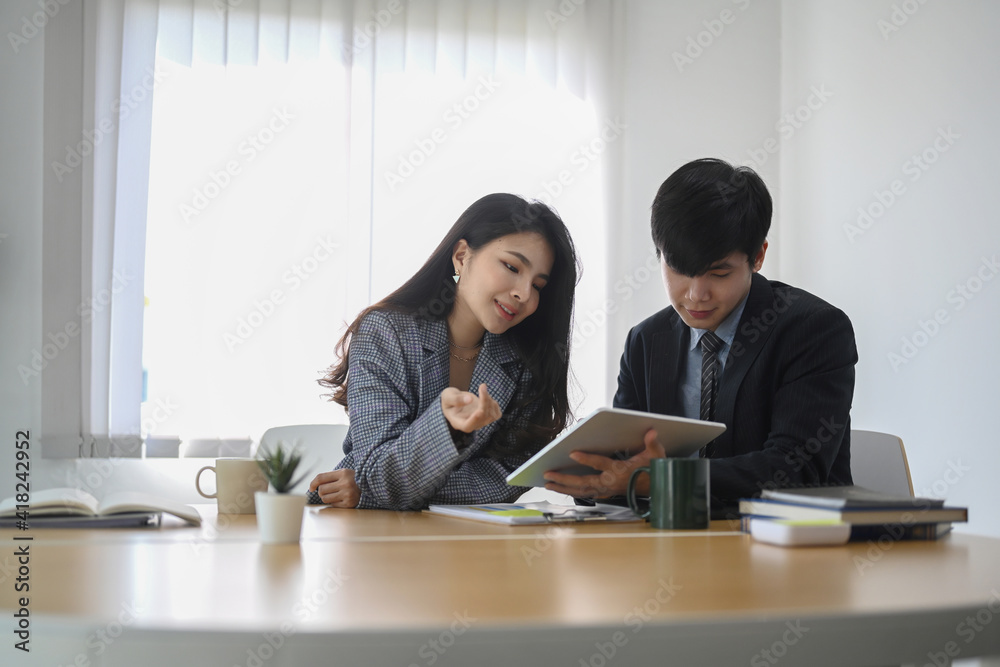 Two young businesspeople using digital tablet and discussing about business growth in modern office. Two young businesspeople using digital tablet and discussing about business growth in modern office.