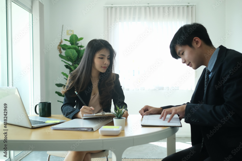 Two successful business people discussing company financial strategy and sitting together in modern office. Two successful business people discussing company financial strategy and sitting together in modern office.