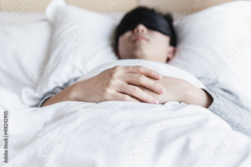 Young man wearing eyeshade is sleeping in bed 
