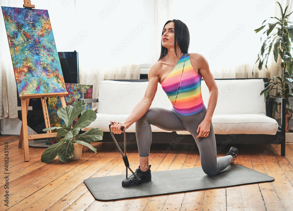 Concentrated on her workout middle aged sportswoman poses on camera exercising on mat at home. Sportive lifestyle and bodycare. Concentrated on her workout middle aged sportswoman poses on camera exercising on mat at home. Sportive lifestyle and bodycare.