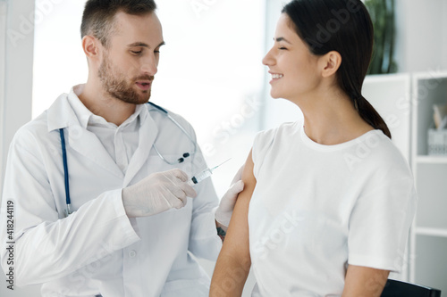 doctor in protective gloves injects a woman's shoulder from covid-19 vaccination