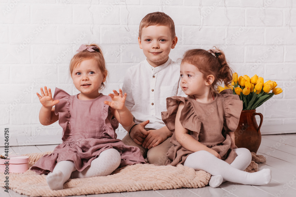 Happy children play in a room with flowers. Brother and sisters together Happy children play in a room with flowers. Brother and sisters together