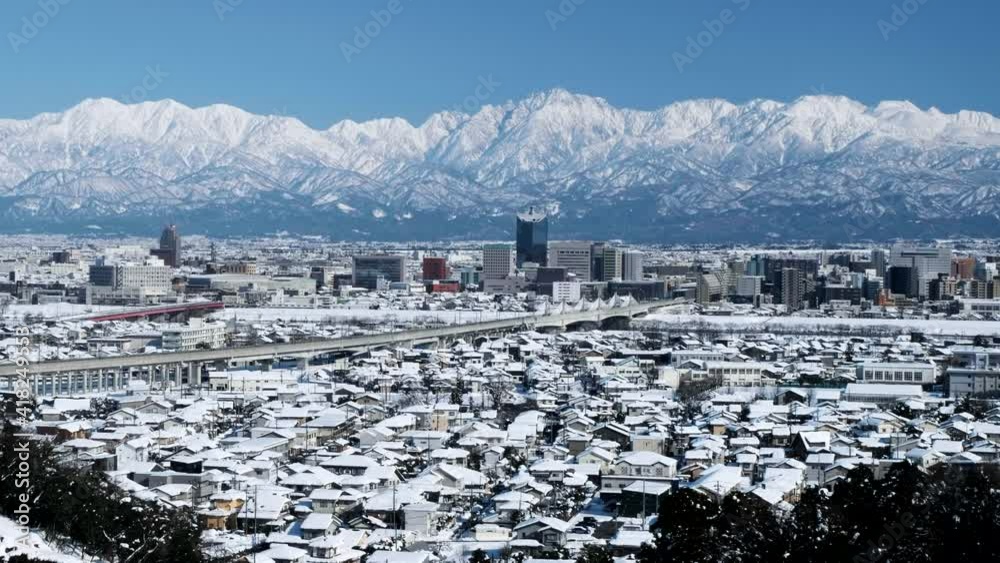 金沢行北陸新幹線走行が走る神通川橋梁と雪に覆われた富山市街地2021.2.19