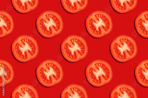 Seamless pattern from slices of ripe tomatoes on a red background