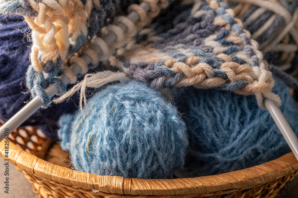 Knitting supplies close-up. Balls of knitting wool in a round wicker basket. Knitting supplies close-up. Balls of knitting wool in a round wicker basket.