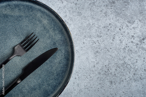 An empty plate and cutlery on a gray table. Top view. Copy space for text.