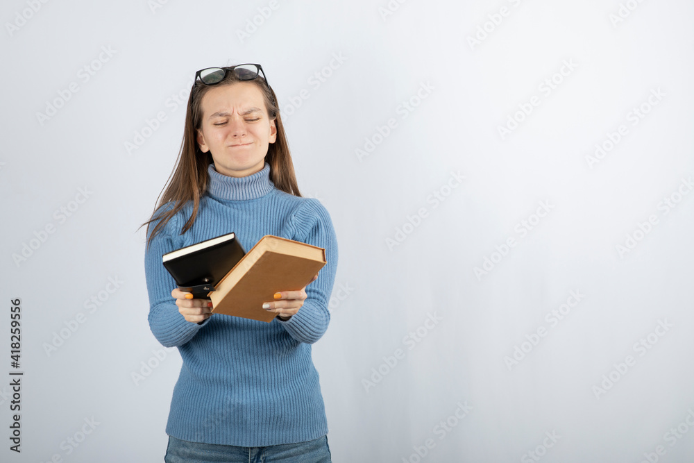 Portrait of a girl in eyeglasses holding two books on white-gray background Portrait of a girl in eyeglasses holding two books on white-gray background