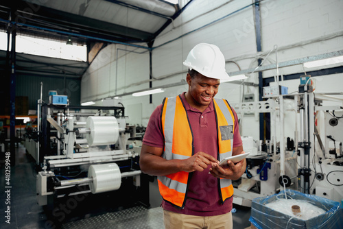 Smiling young african male employee using digital tablet while working in industry
