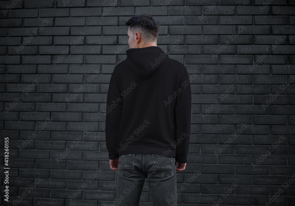 Тemplate of black men's clothing with long sleeves on a young guy on a brick wall background, back, sweatshirt with a hood. Тemplate of black men's clothing with long sleeves on a young guy on a brick wall background, back, sweatshirt with a hood.