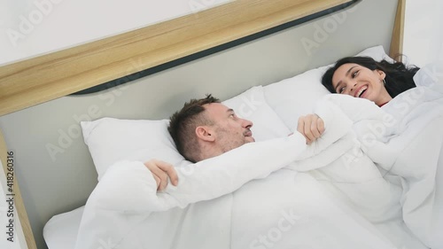 Man and woman couple in casual winter outfit wake up on bed in the morning with happy and romantic mood in bedroom