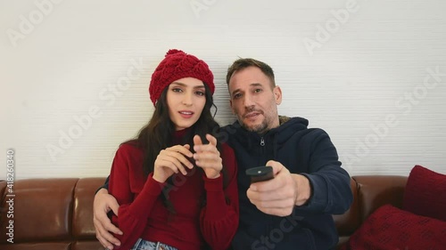 Man and woman couple in casual winter outfit sitting in living room watching tv with happy and romantic mood
