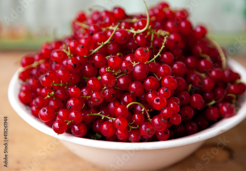 Currants in a bowl on a weeden background. Red berry. Vitamin berries. Copy space