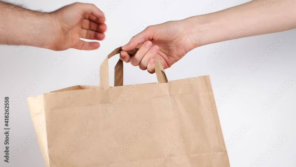 man hand give craft food paper bag to woman hands, Food delivery, takeaway, shopping online concept. 4k resolution.