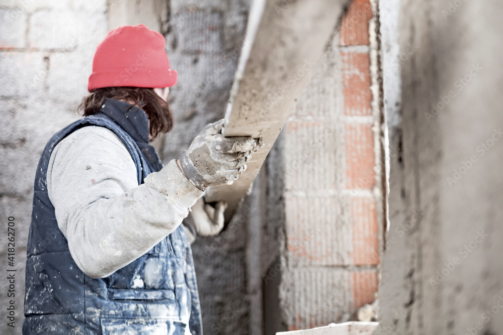 Real construction worker working on a wall inside the new house. Real construction worker working on a wall inside the new house.
