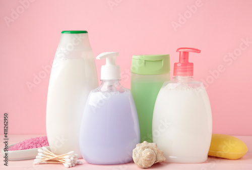 Collection of various beauty hygiene containers on pink background. Shower gel